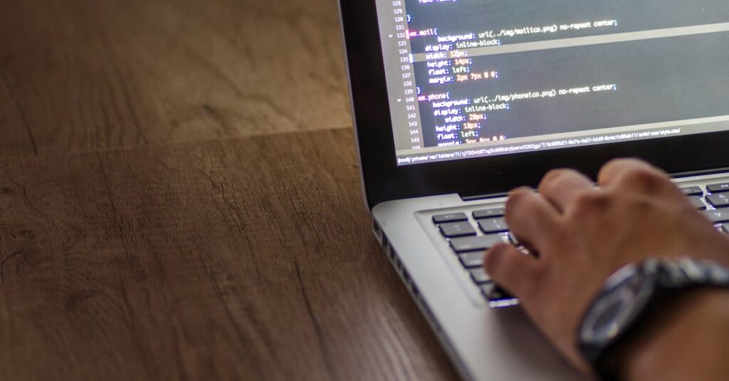 A person is typing code on a laptop, focusing on the screen with programming script.